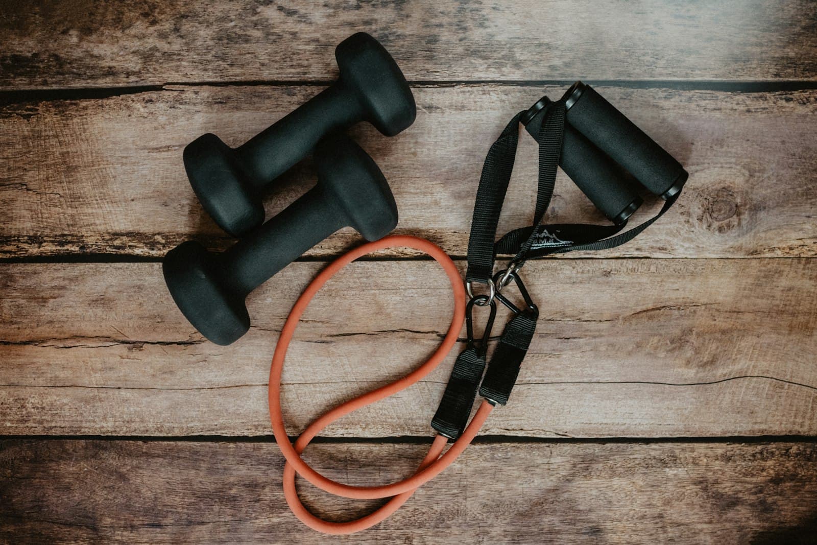 Dumbbells and a resistance band on a wooden floor