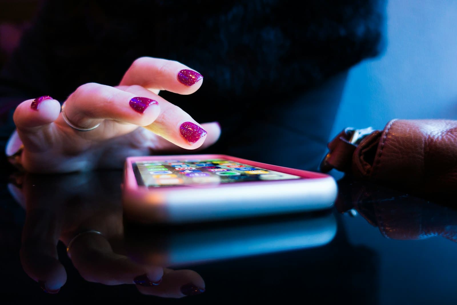 A hand tapping a glowing phone screen in neon light