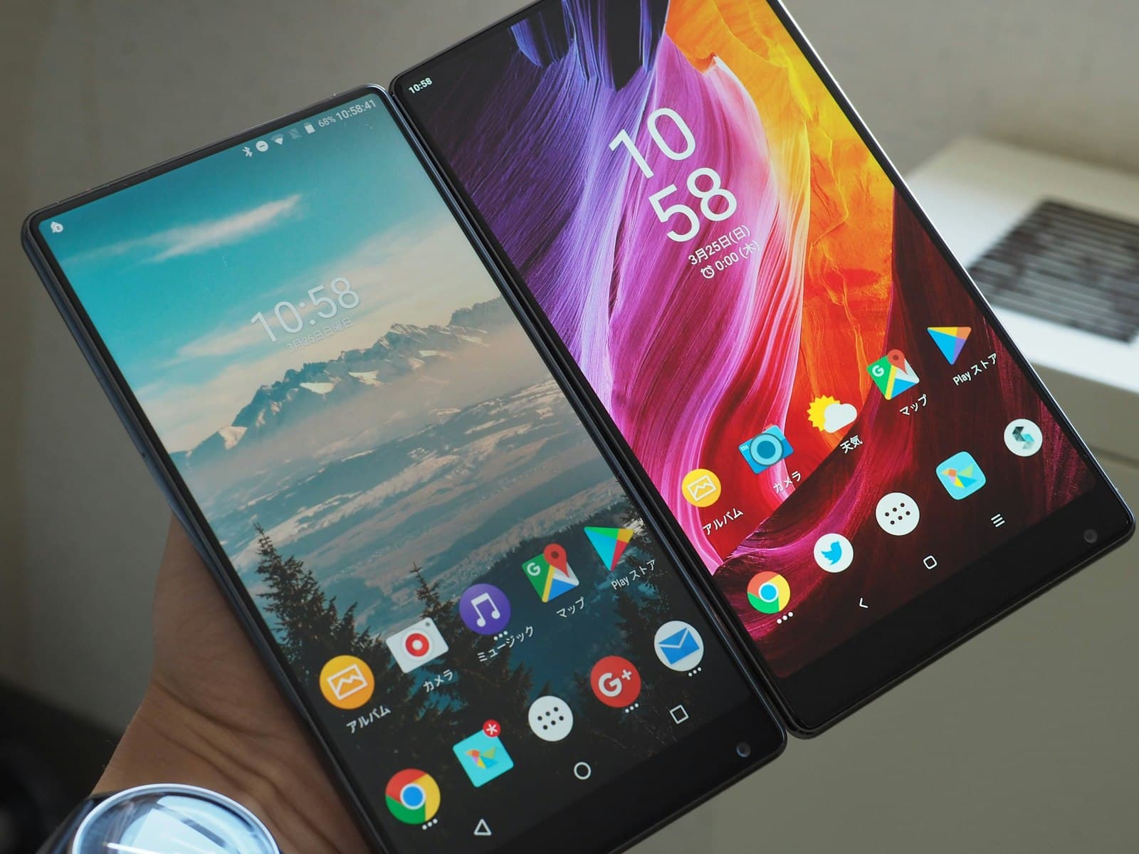 A hand holding two Android phones side by side