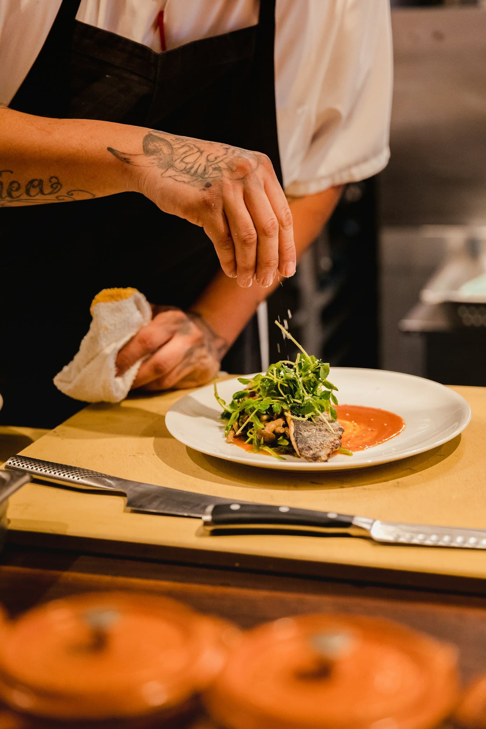 A chef plating a dish with fresh greens