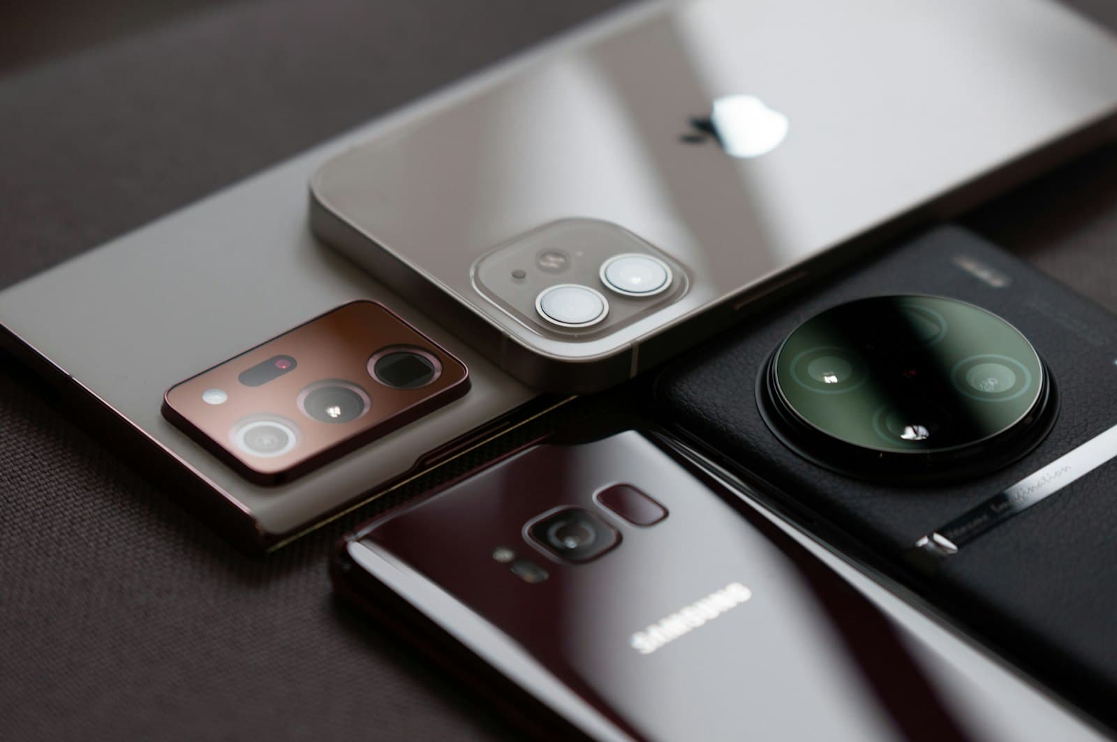 Four modern smartphones lying face down, an iPhone among Samsung and other Android phones